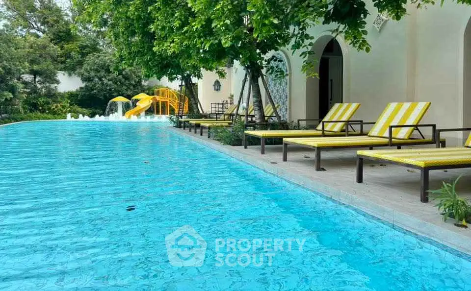 Luxurious outdoor pool area with sun loungers and lush greenery, perfect for relaxation.