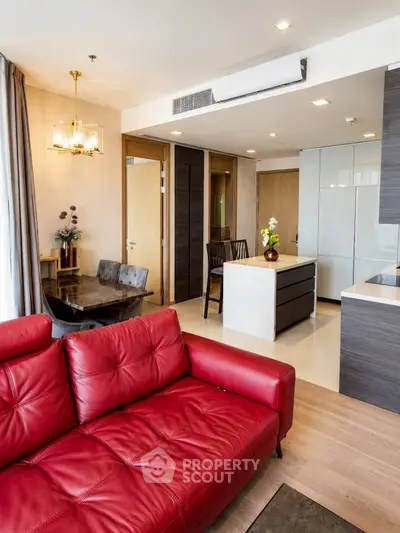 Modern open-layout living room with red leather sofa and stylish kitchen area.