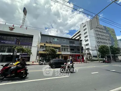 Street view of commercial buildings with modern architecture and busy traffic in urban setting.