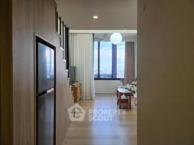 Modern living room with large windows offering stunning city views, featuring sleek wooden flooring and contemporary decor.
