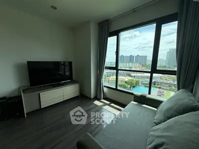Modern living room with large window offering stunning cityscape view, featuring sleek furniture and natural light.