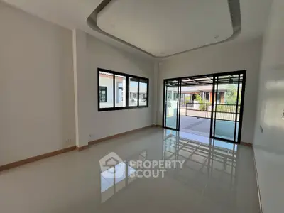 Spacious modern living room with large windows and sliding glass doors opening to a patio.
