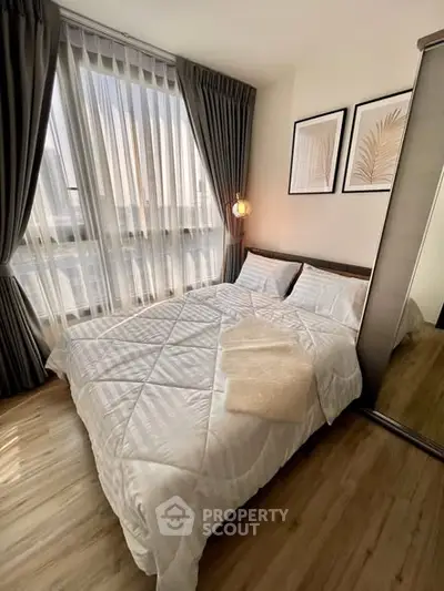 Cozy bedroom with large window, elegant curtains, and stylish decor for a serene living experience.