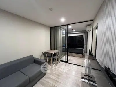 Modern living room with sleek design and glass partition leading to bedroom