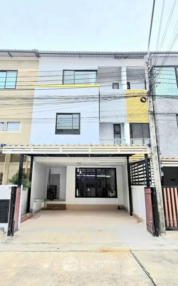 Modern three-story townhouse with covered parking and contemporary facade design.