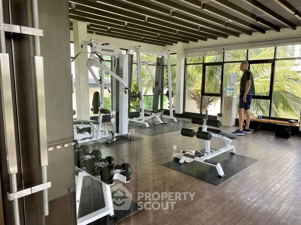 Modern gym with state-of-the-art equipment and large windows offering a lush green view.