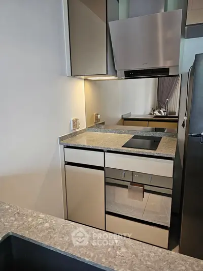 Modern kitchen with sleek cabinetry and built-in oven, featuring a compact and efficient design.