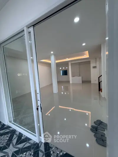 Modern open-plan living area with sleek tile flooring and recessed lighting.
