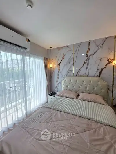 Luxurious bedroom with marble accent wall and large window offering natural light.