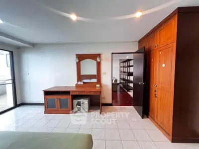 Spacious bedroom with wooden furniture and ample storage in modern apartment