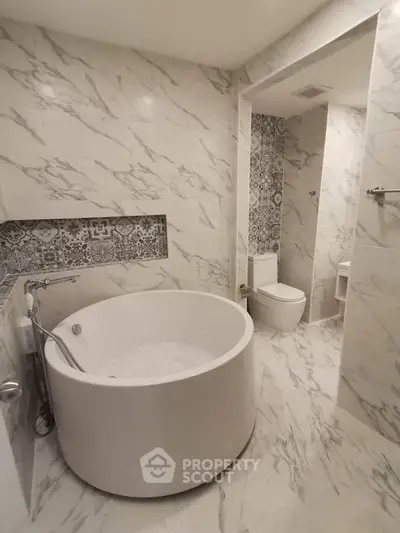 Luxurious marble bathroom with round bathtub and elegant tile accents.