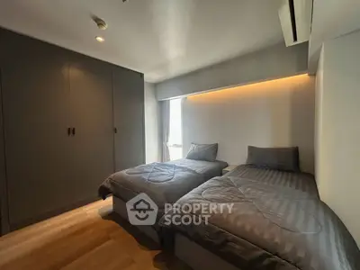 Modern bedroom with twin beds and sleek wardrobe, featuring ambient lighting and minimalist design.