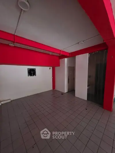 Spacious tiled room with vibrant red beams and white walls, ideal for creative renovation.