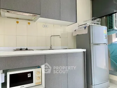 Modern kitchen with sleek cabinets, gas stove, and stainless steel fridge in a compact layout.