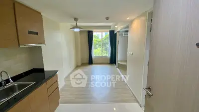 Spacious apartment with modern kitchen and bright living area, featuring large window with green view.