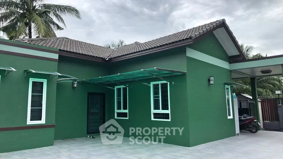 Charming green single-story house with modern design and spacious driveway, perfect for family living.