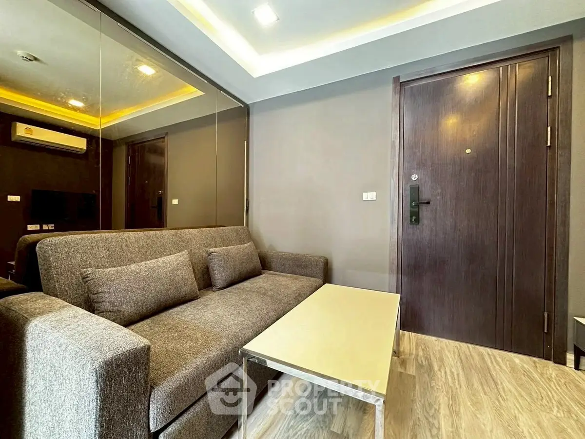 Modern living room with sleek sofa and mirrored wall in a stylish apartment.