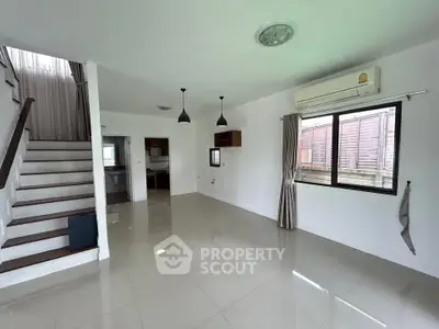 Spacious modern living room with staircase and large windows in a bright, airy home.