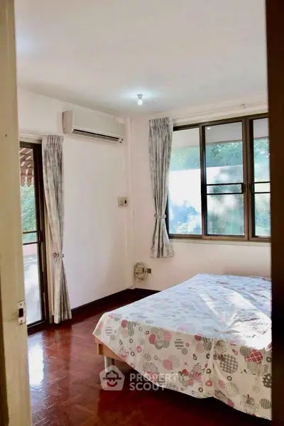 Cozy bedroom with large windows and natural light in a serene setting.