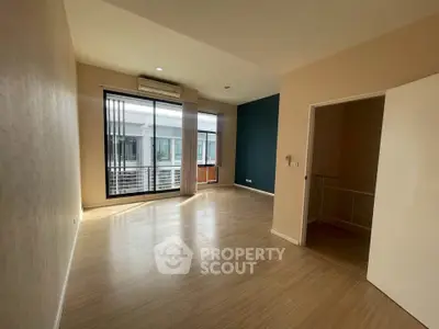 Spacious empty room with large windows and wooden flooring in modern apartment.
