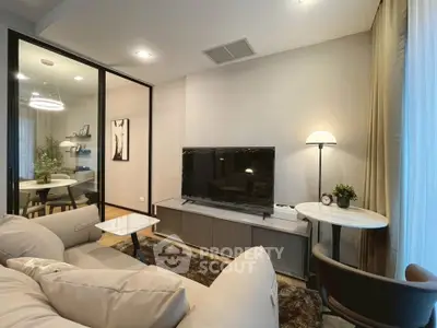 Modern living room with stylish decor and cozy seating area, featuring a sleek TV setup and elegant lighting.