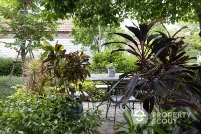 Lush garden with outdoor seating area under leafy canopy