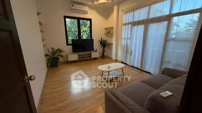 Cozy living room with large windows, wooden flooring, and modern furniture, perfect for relaxation.