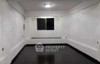 Spacious empty room with dark flooring and bright lighting, ideal for customization.