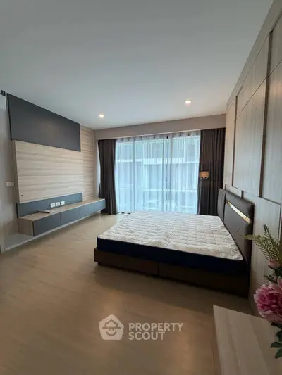 Spacious modern bedroom with large window and stylish wooden accents.