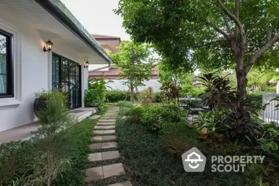 Charming garden pathway leading to a cozy home with lush greenery and outdoor seating area.