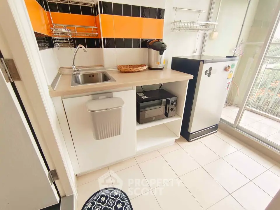 Modern kitchen with sleek appliances and vibrant backsplash in a cozy apartment setting.