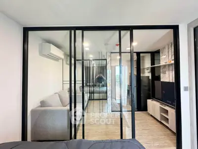 Modern living room with glass partition, sleek furniture, and air conditioning unit.