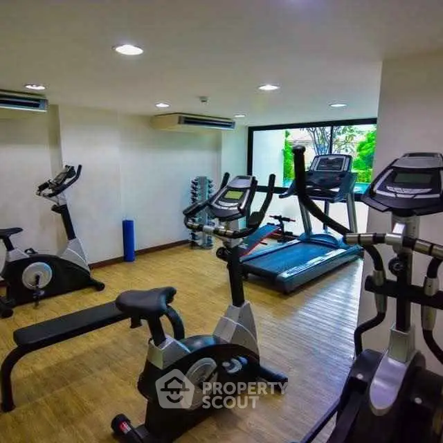 Modern gym with exercise equipment and large window view in residential building.