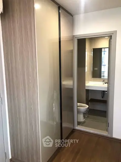 Modern bathroom with sleek design and wooden flooring, featuring a glass shower enclosure and stylish fixtures.