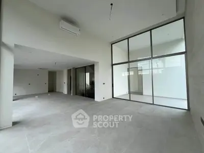 Spacious modern living room with high ceilings and large windows in a luxury apartment.
