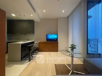 Modern living room with sleek furniture and city view, featuring open kitchen layout and stylish decor.