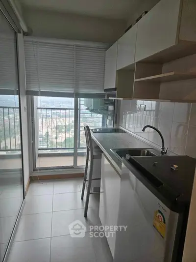 Compact kitchen with balcony view, featuring modern appliances and sleek cabinetry, perfect for urban living.
