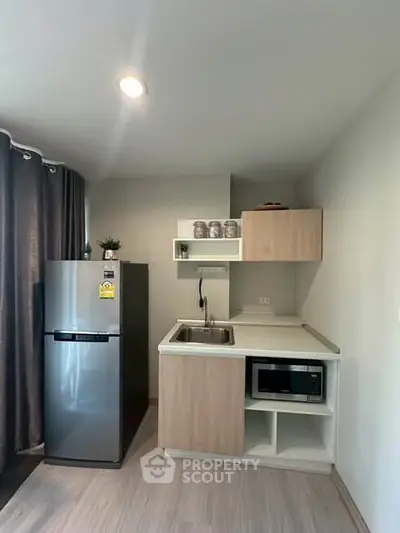 Modern compact kitchen with sleek appliances and stylish cabinetry in a cozy apartment setting.
