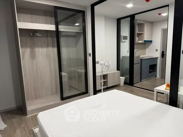 Modern studio apartment with open layout and sleek design, featuring a compact kitchen and spacious wardrobe.
