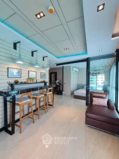 Modern open-layout living room with stylish bar seating and cozy bedroom view.