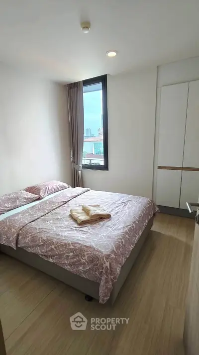 Cozy bedroom with city view, featuring a comfortable bed and modern wardrobe, perfect for urban living.