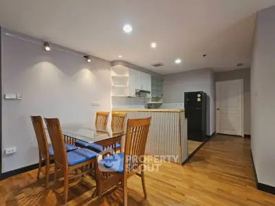 Modern dining area with wooden flooring and sleek kitchen in open layout apartment.