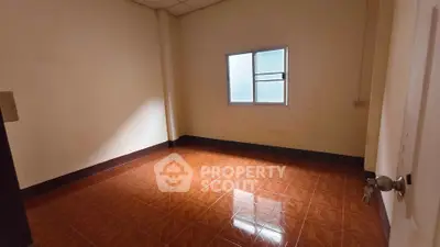 Spacious empty room with tiled floor and window, ideal for customization.