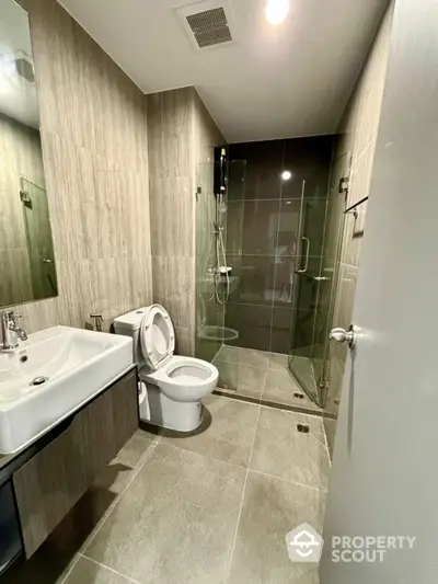 Modern bathroom with glass shower and sleek fixtures in contemporary apartment.