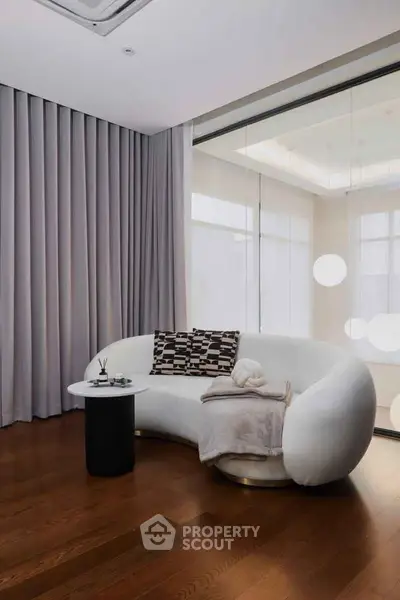 Modern living room with elegant curved sofa and floor-to-ceiling curtains