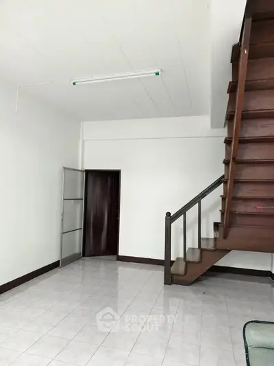 Spacious interior with wooden staircase and tiled flooring, ideal for modern living.