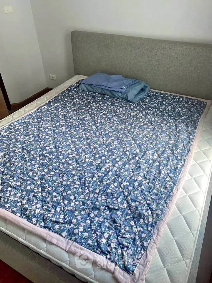 Cozy bedroom with a neatly made bed featuring a floral quilt, perfect for relaxation.