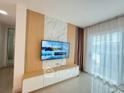 Modern living room with wall-mounted TV and large window for natural light.