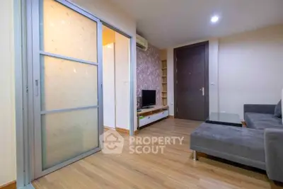 Modern living room with sleek design, wooden flooring, and sliding door for space optimization.