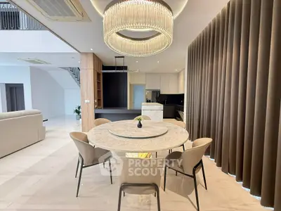 Luxurious modern dining area with elegant chandelier and marble table in open-concept living space.